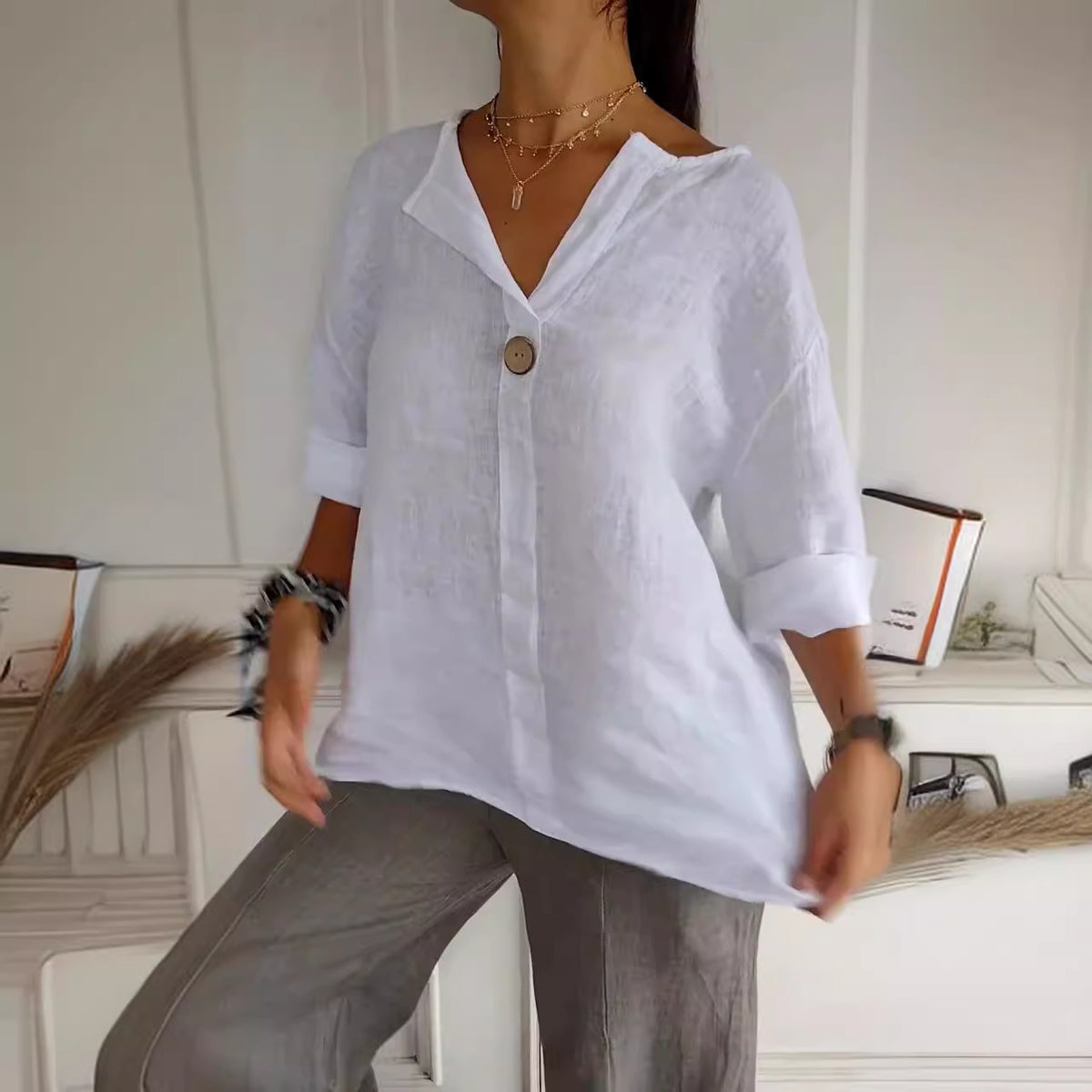 Relaxed button-neck blouse in white worn with grey trousers